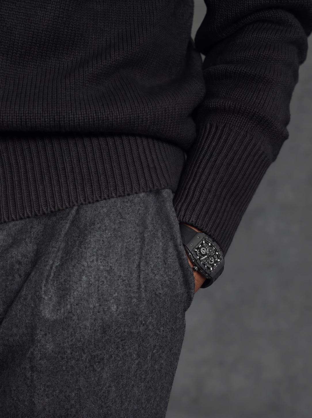 BOLTRON in Black on a hand in the pocket of grey wool trousers, below a black knit sweater