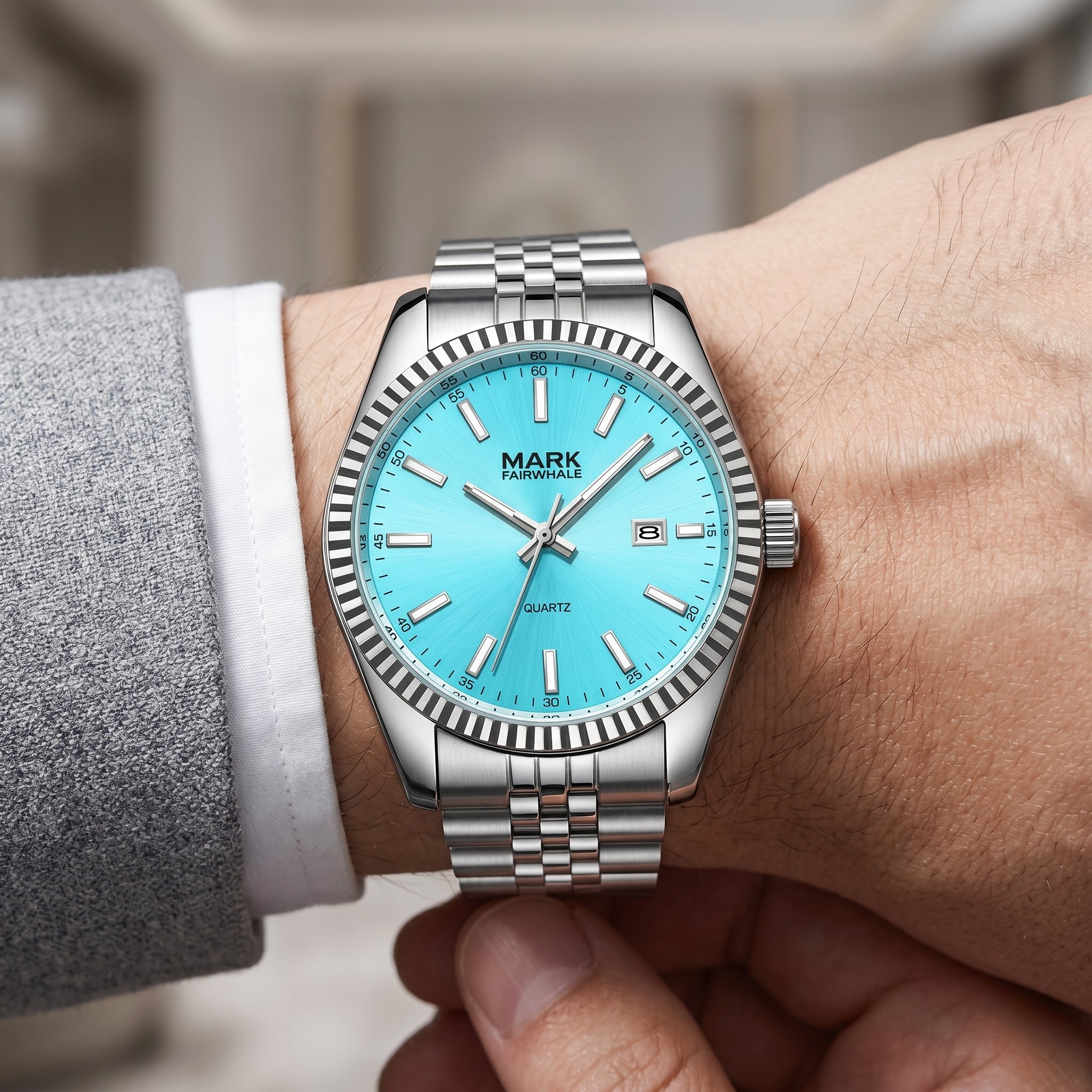 Men’s silver stainless steel watch with turquoise dial close-up on wrist, sharp detailed face, luxury suit lifestyle shot