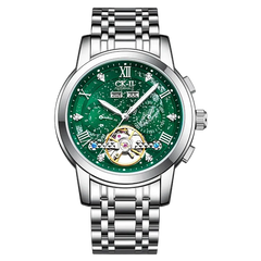 A men's stainless steel wristwatch with a green skeleton dial and a visible gold-tone automatic movement at the 6 o'clock position. The dial features Roman numeral hour markers, crystal hour indices, and a matching green metal link bracelet.