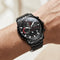 Black wristwatch with detailed face on a wrist against a neutral background