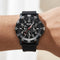 Black wristwatch with detailed face on a wrist against a neutral background