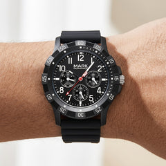 Black wristwatch with detailed face on a wrist against a neutral background