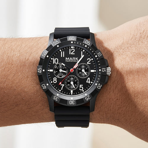 Black wristwatch with detailed face on a wrist against a neutral background