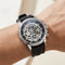 Black wristwatch with a detailed face on a wrist against a neutral background