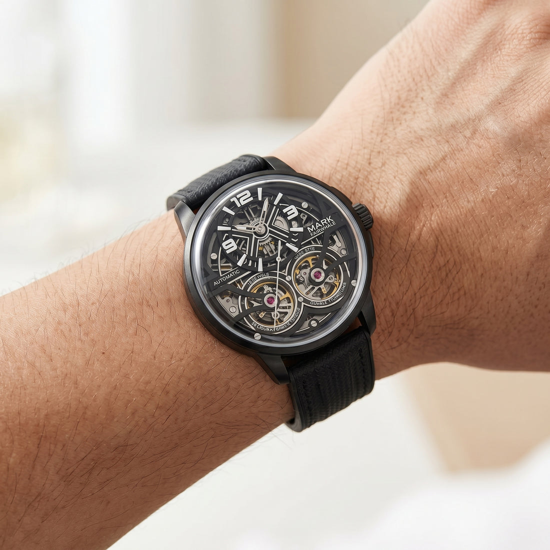 Black wristwatch with detailed face on a wrist against a neutral background