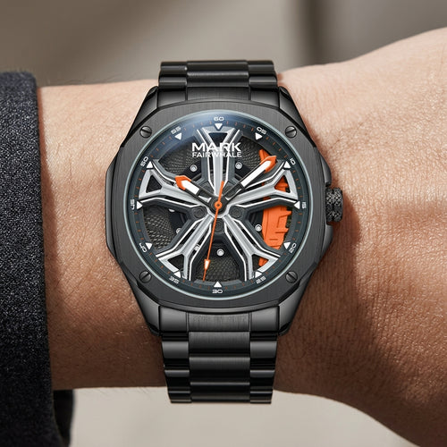 Black wristwatch with orange accents on a wrist against a neutral background