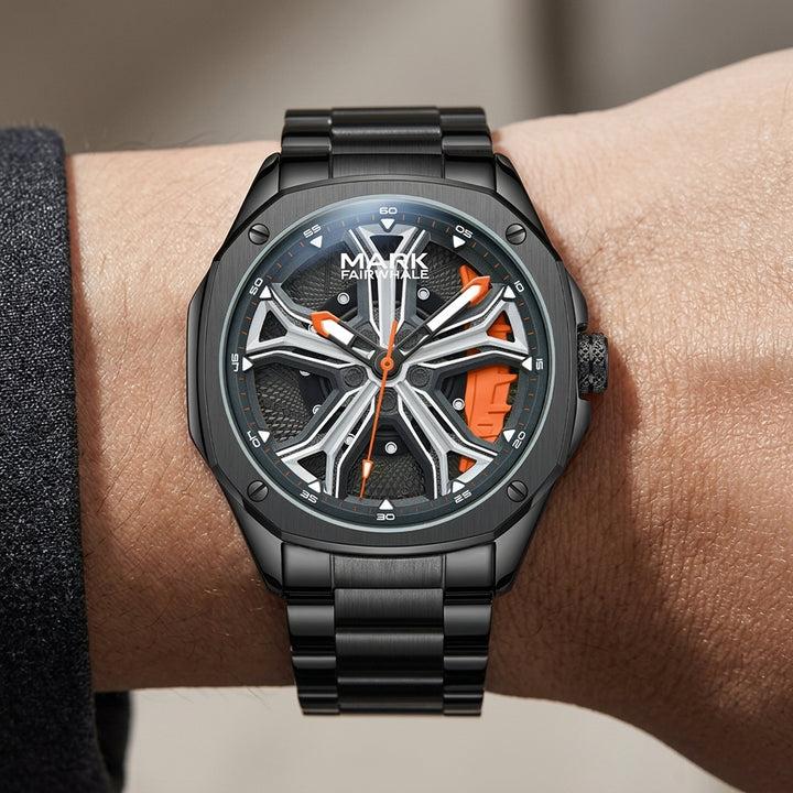 Black wristwatch with orange accents on a wrist against a neutral background