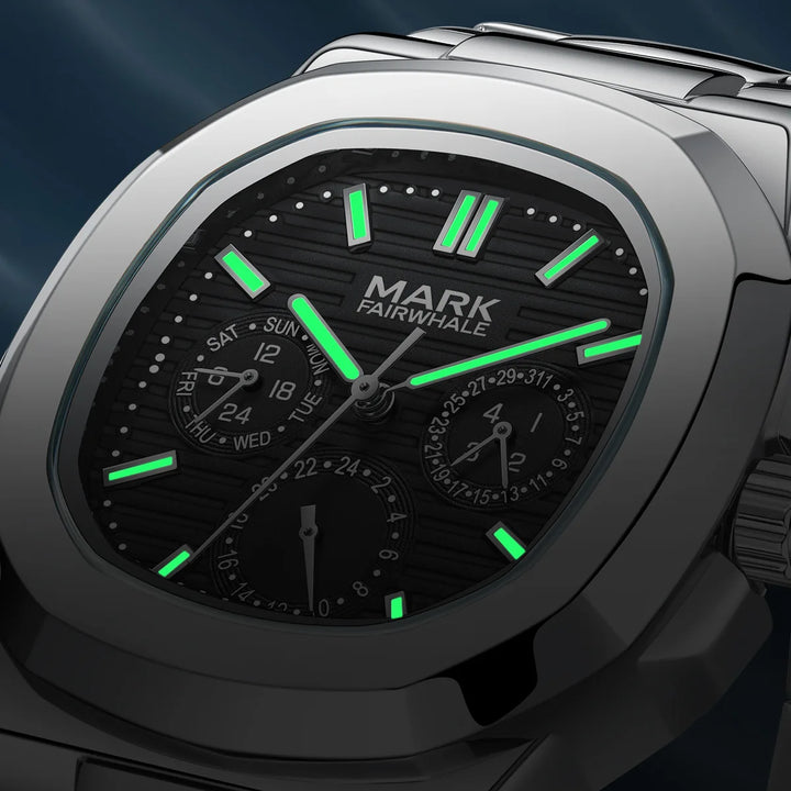 Close-up of Mark Fairwhale 5019 LUMENIX black dial glowing with luminous hands in low light.