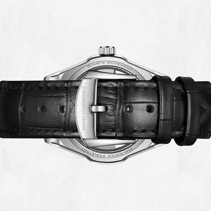 Close-up of a Mark Fairwhale watch with black leather strap and silver case on a white background
