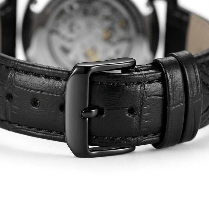 Close-up of a black leather watch strap with a metallic buckle on a white background