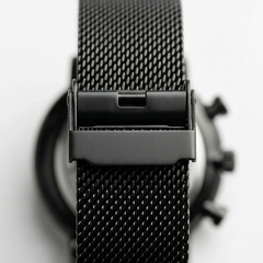 Close-up of a black mesh watch strap with 'FAIRWHALE' branding on a blurred background