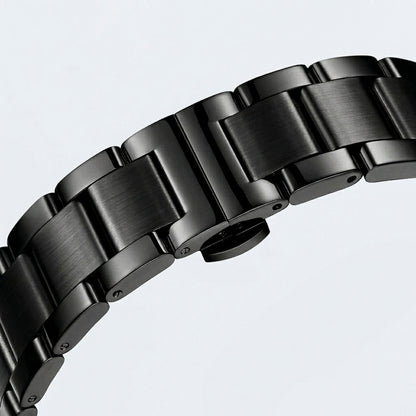 Close-up of a black metal watch strap on a light gray background