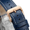Close-up of a blue leather watch strap with a rose gold buckle on a blurred background
