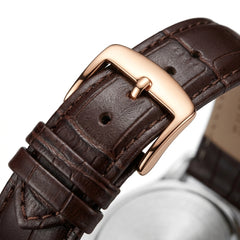 Close-up of a brown leather watch strap with a rose gold buckle on a white background