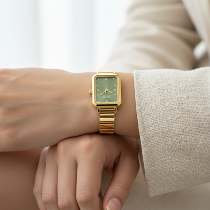 Gold watch with a green face on a wrist against a neutral background