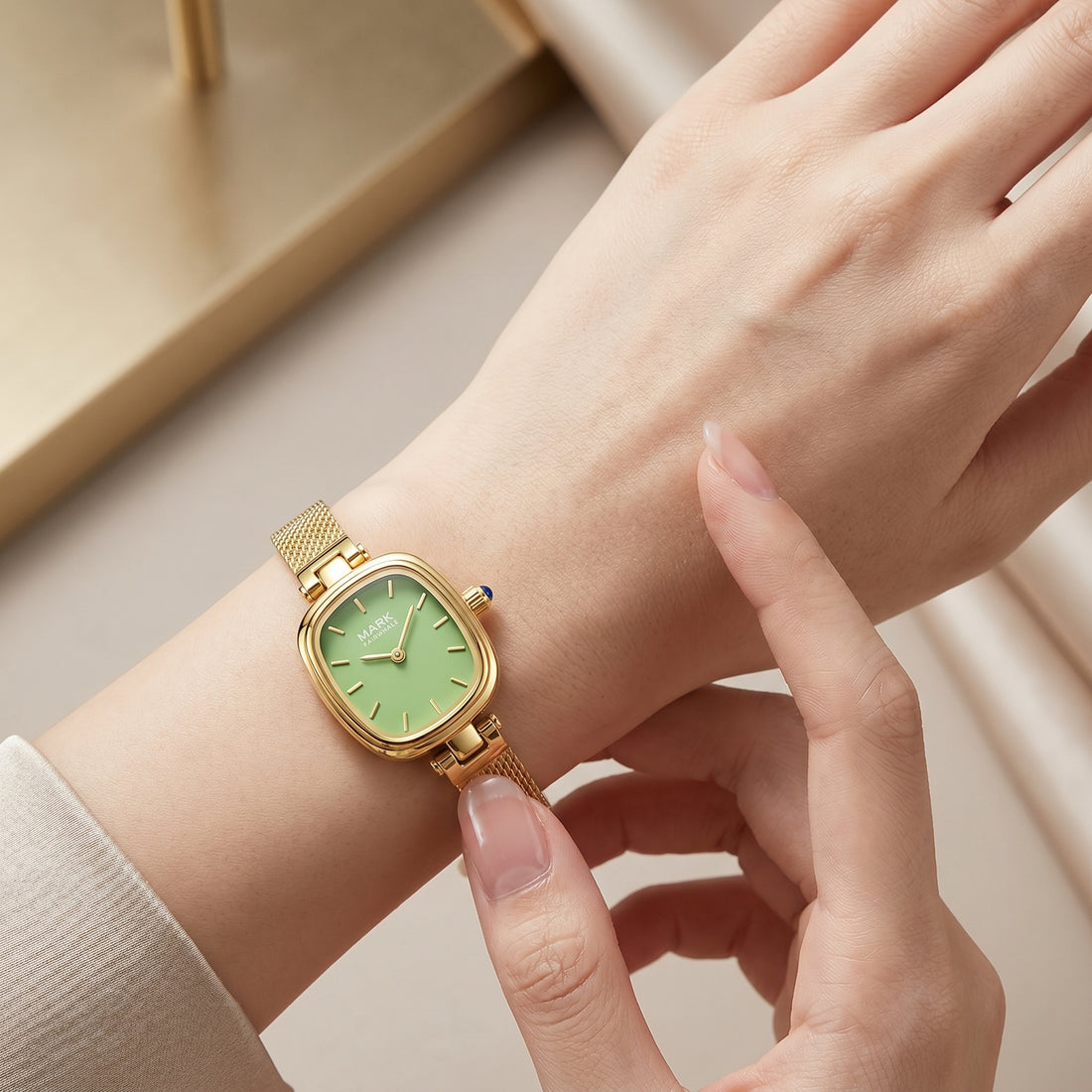 Gold watch with a green face on a wrist, held by a hand