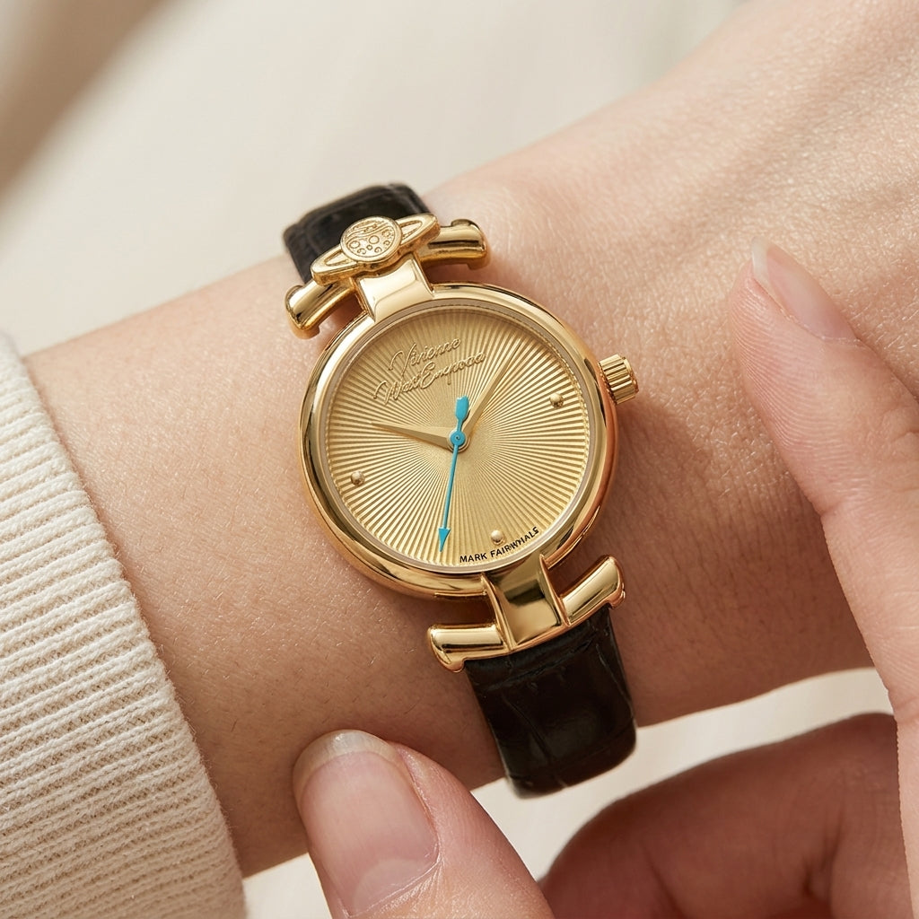 Gold watch with black strap on wrist against a neutral background