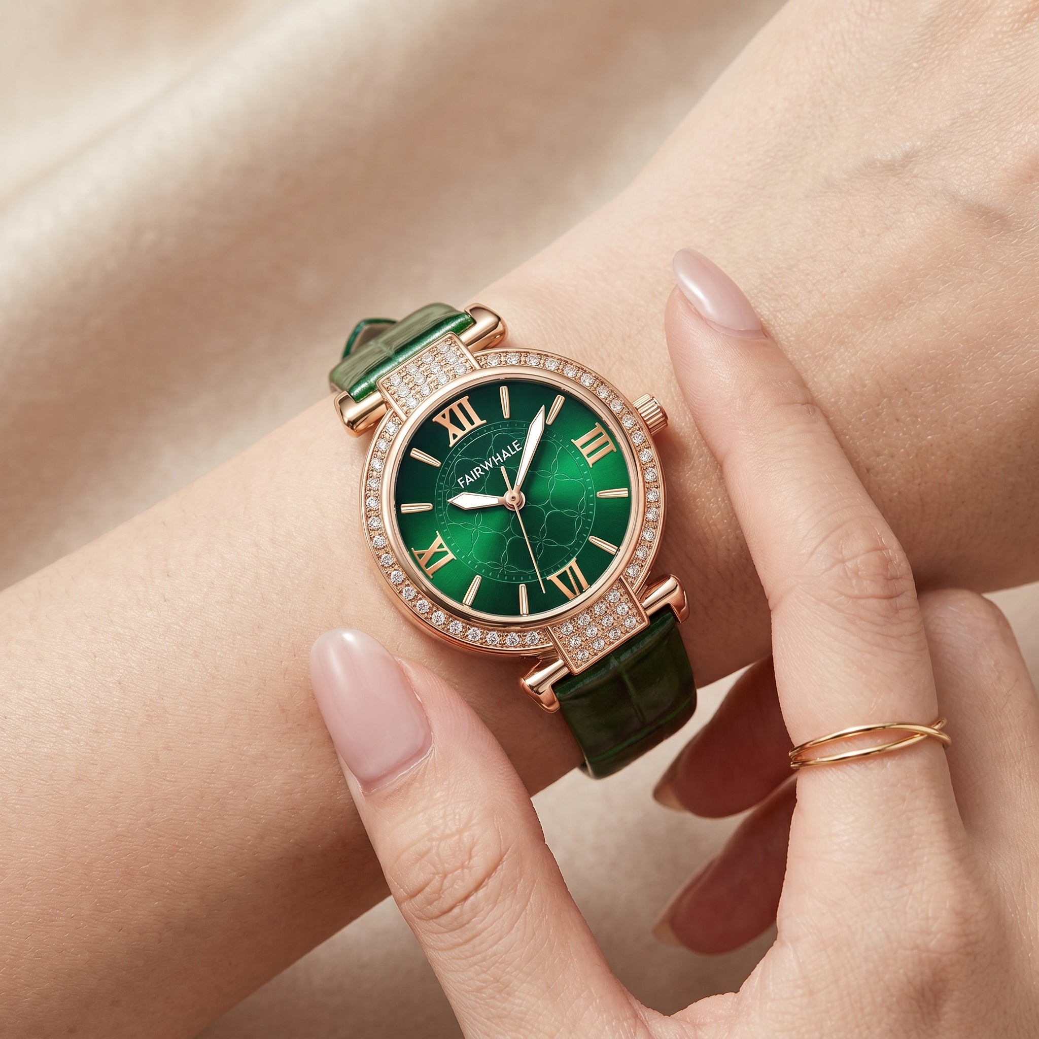 Green watch with rose gold case on a wrist against a beige background