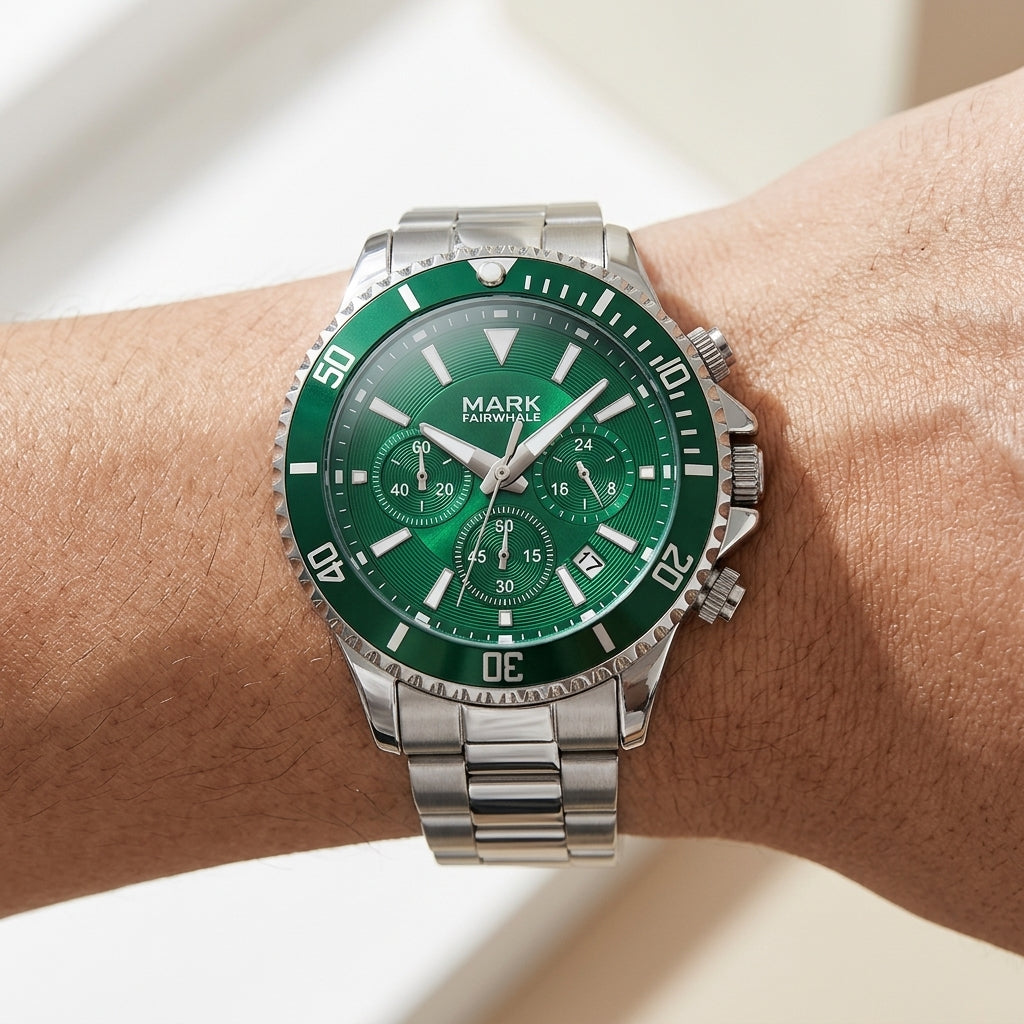 Green watch with silver case and bracelet on a wrist against a neutral background