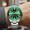 Green watch with silver strap on a wrist against a blurred background