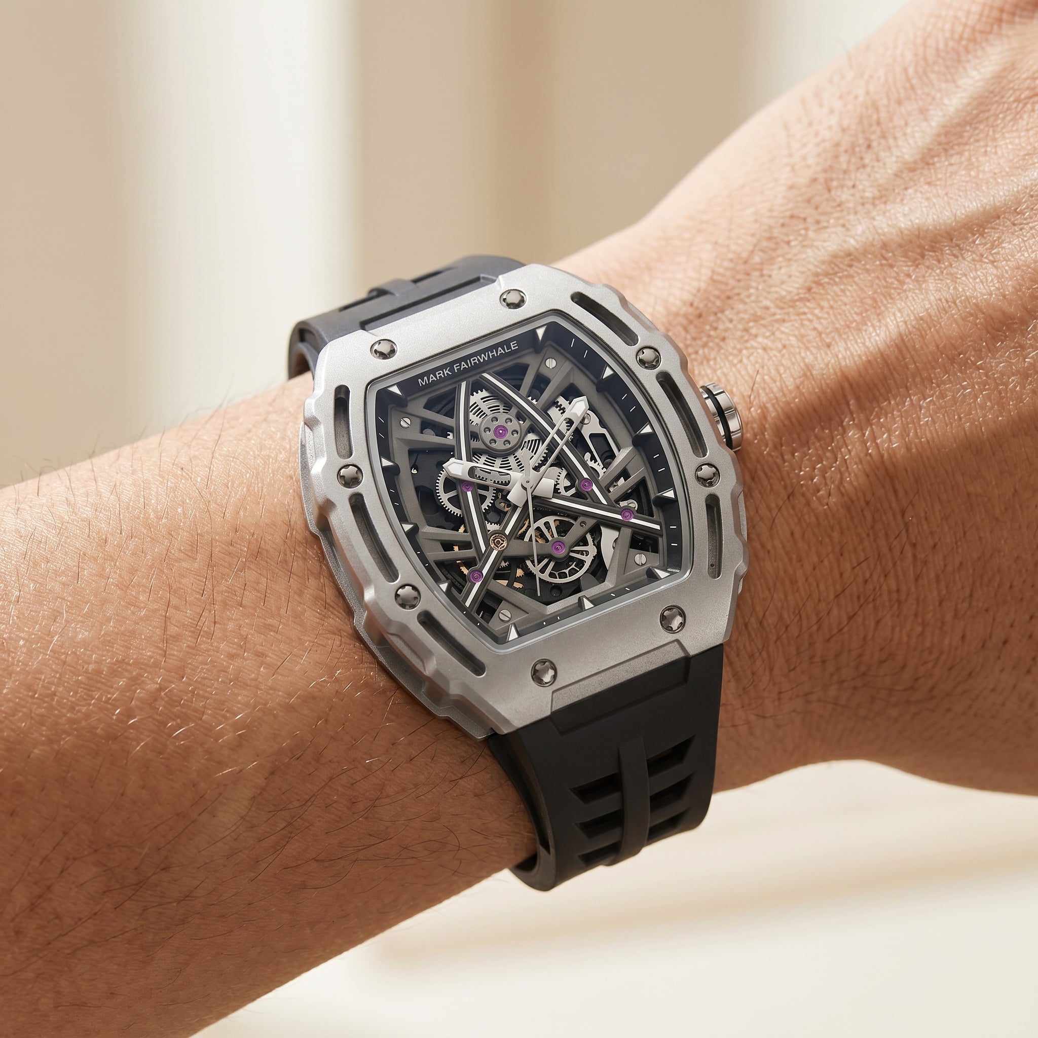 Luxury watch with black strap and silver case on a wrist against a neutral background