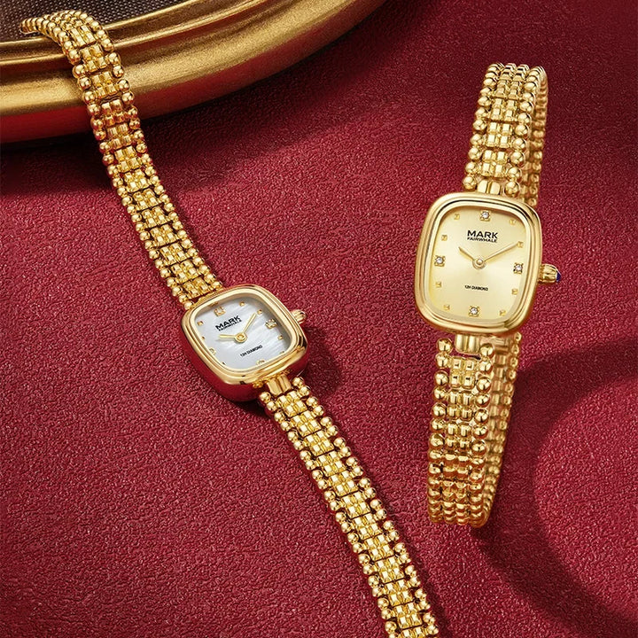 Two Mark Fairwhale 3060 LUMEA gold watches displayed on beige background highlighting elegant bracelet design
