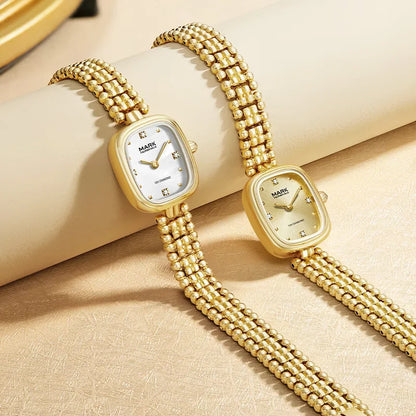 Two Mark Fairwhale 3060 LUMEA gold watches displayed on beige background highlighting elegant bracelet design