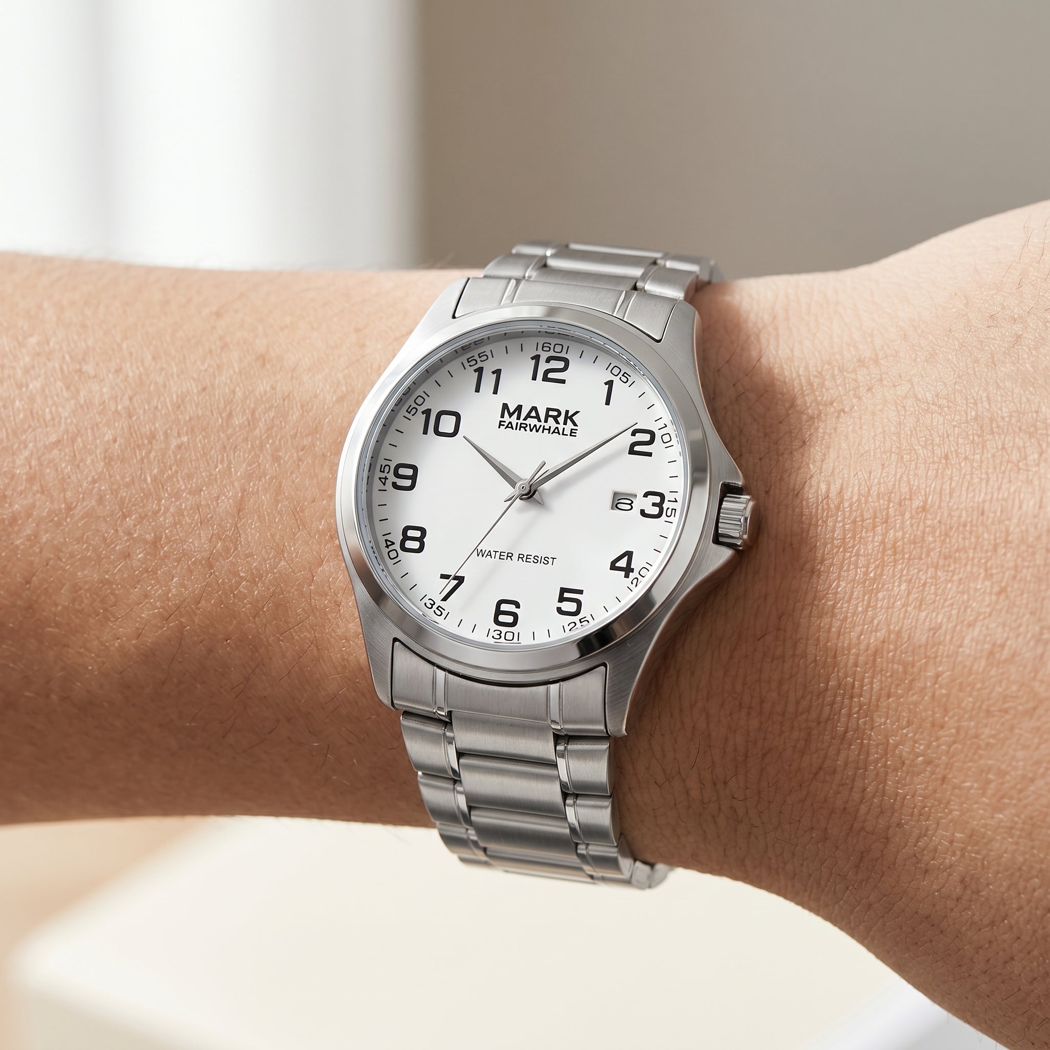 Mark Fairwhale men’s quartz watch with silver stainless steel case and bracelet, white dial with black Arabic numerals, worn on wrist in close up lifestyle view
