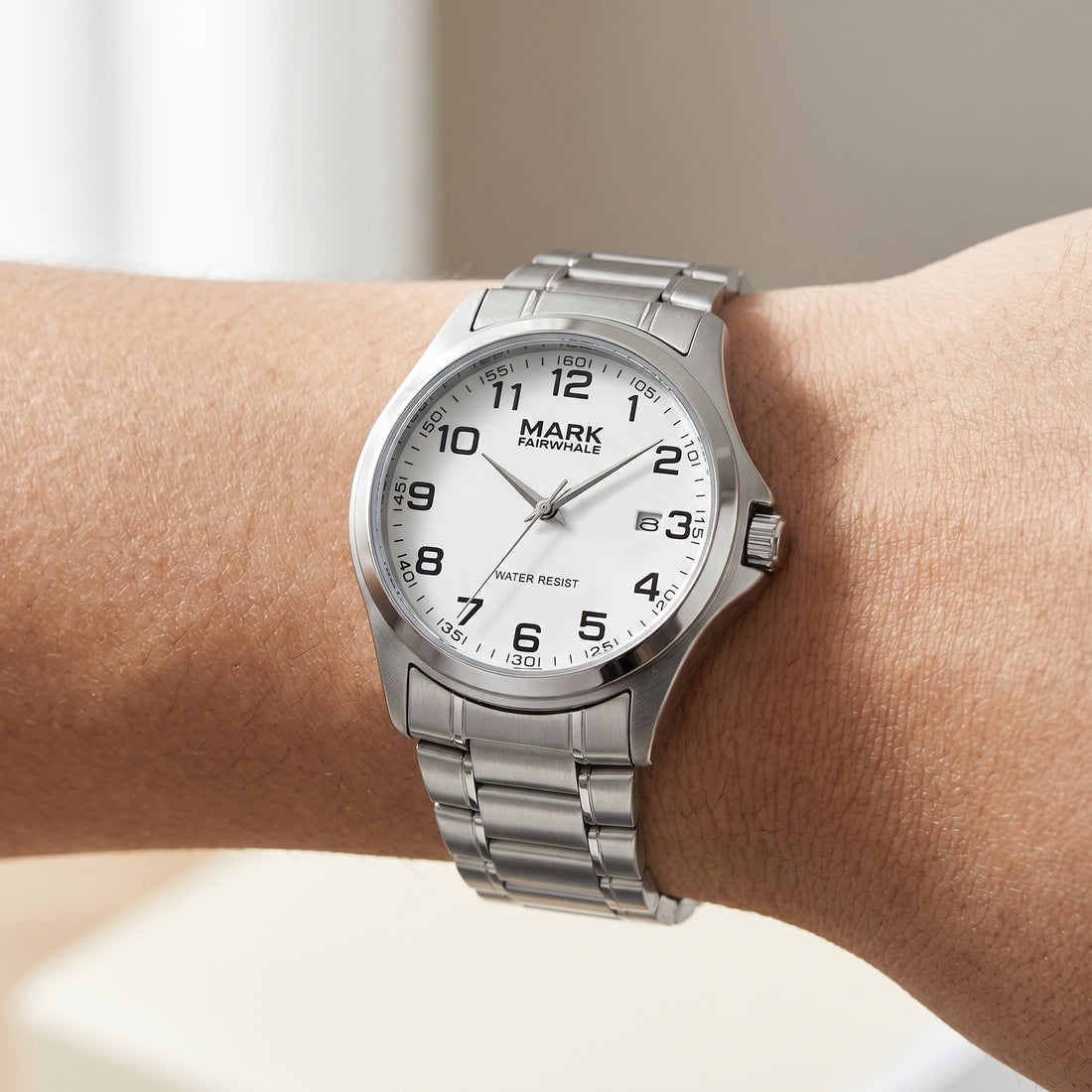 Mark Fairwhale men’s quartz watch with silver stainless steel case and bracelet, white dial with black Arabic numerals, worn on wrist in close up lifestyle view