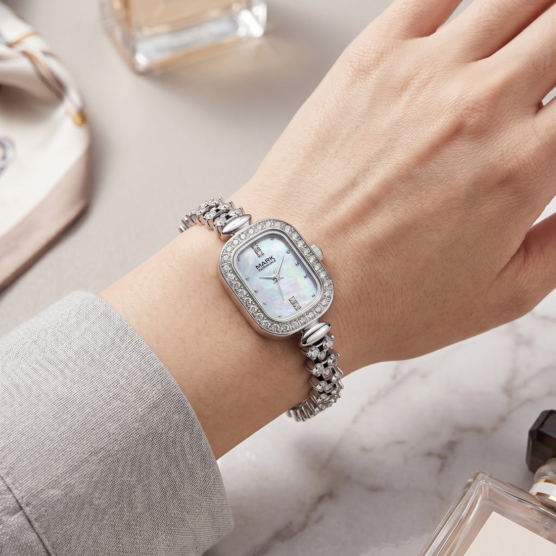 Mark Fairwhale silver crystal watch with mother-of-pearl dial on feminine wrist over marble surface