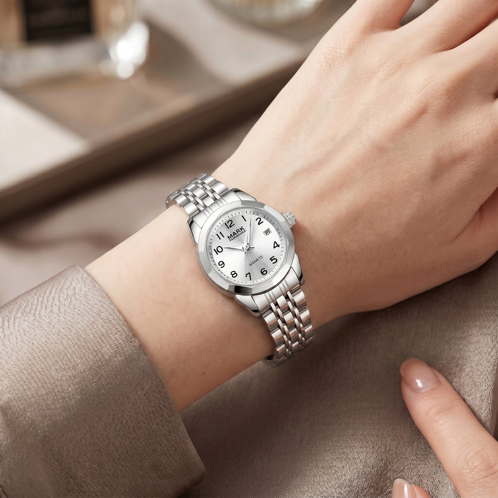Mark Fairwhale women's silver quartz watch with white dial, Arabic numerals, date display, polished metal bracelet, and elegant wrist lifestyle close up