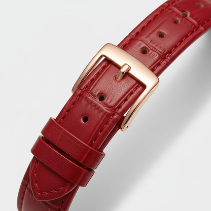 Red leather watch strap with a gold buckle on a light gray background