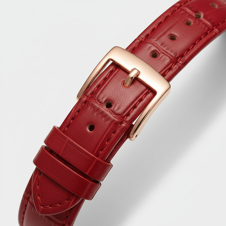 Red leather watch strap with a gold buckle on a light gray background