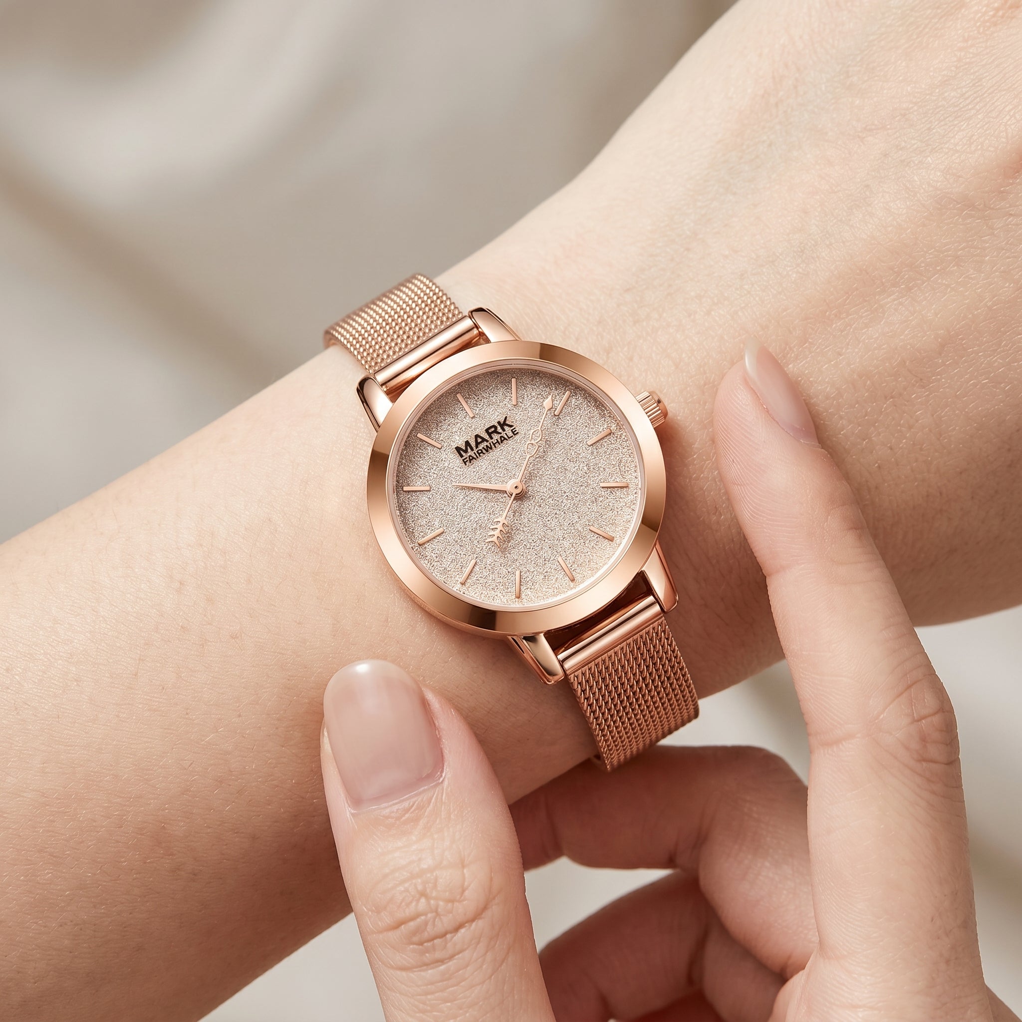 Rose gold watch on a wrist with a neutral background
