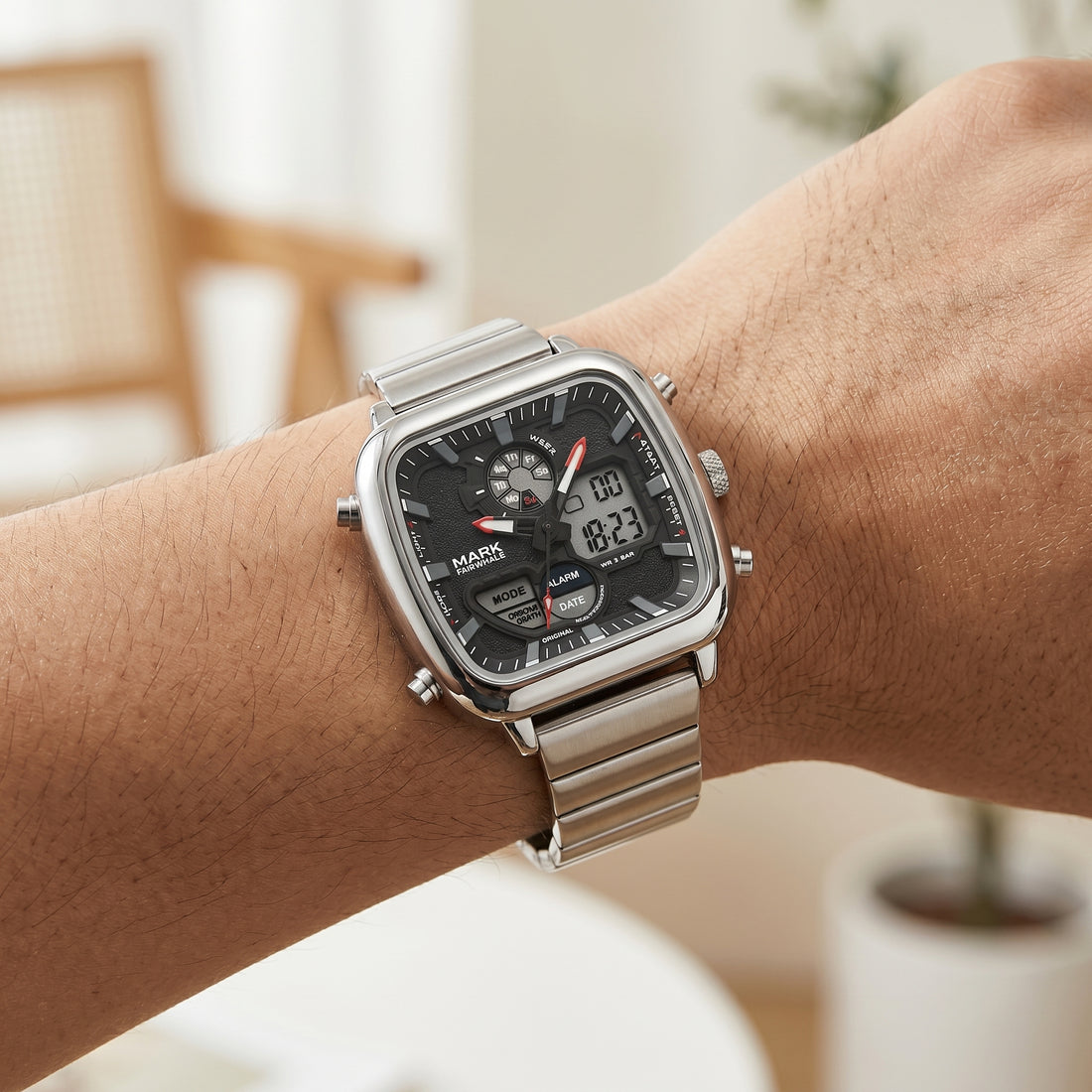 Silver digital watch on a wrist with a blurred indoor background