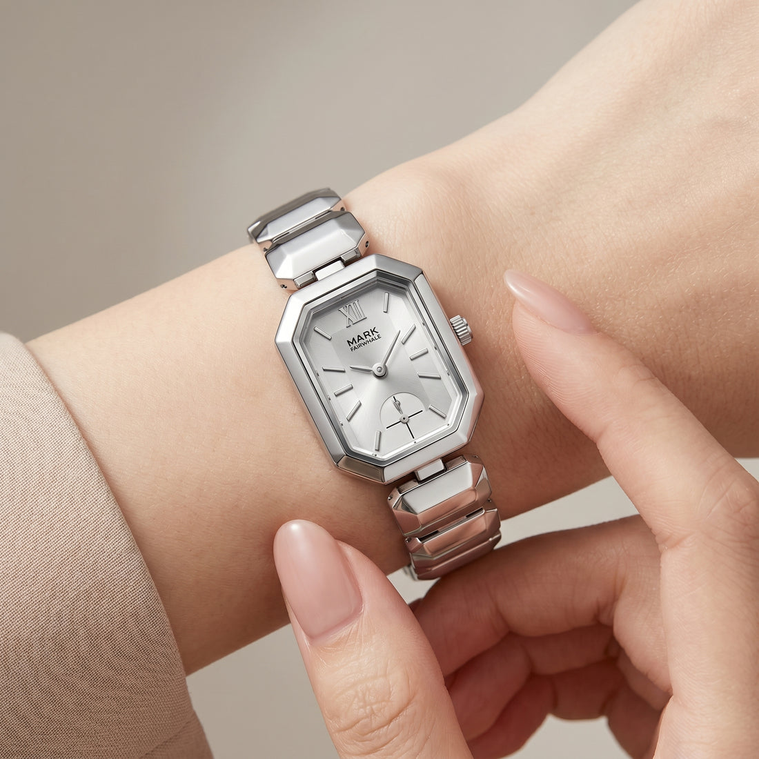 Silver watch on a wrist with a neutral background