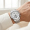 Silver watch on a wrist with a blurred indoor background
