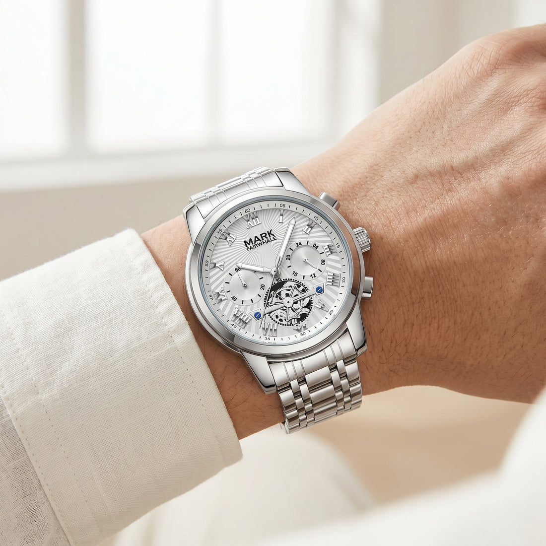 Silver watch on a wrist with a blurred indoor background