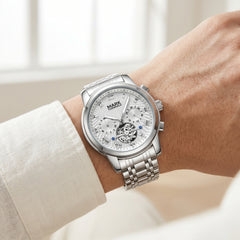 Silver watch on a wrist with a blurred indoor background