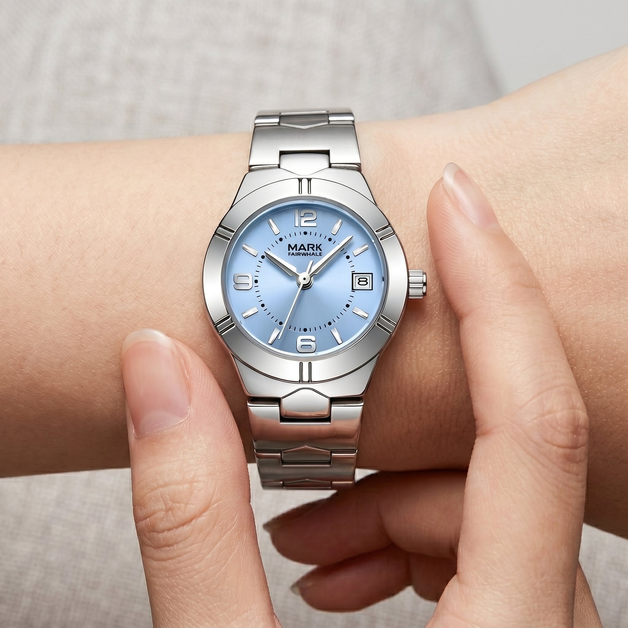 Silver watch with a blue face on a wrist against a neutral background