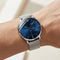 Silver watch with a blue face on a wrist against a neutral background
