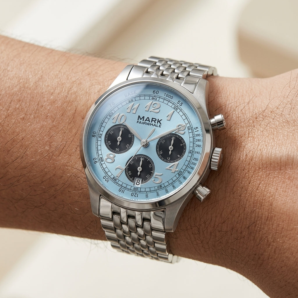 Silver watch with a blue face on a wrist against a neutral background