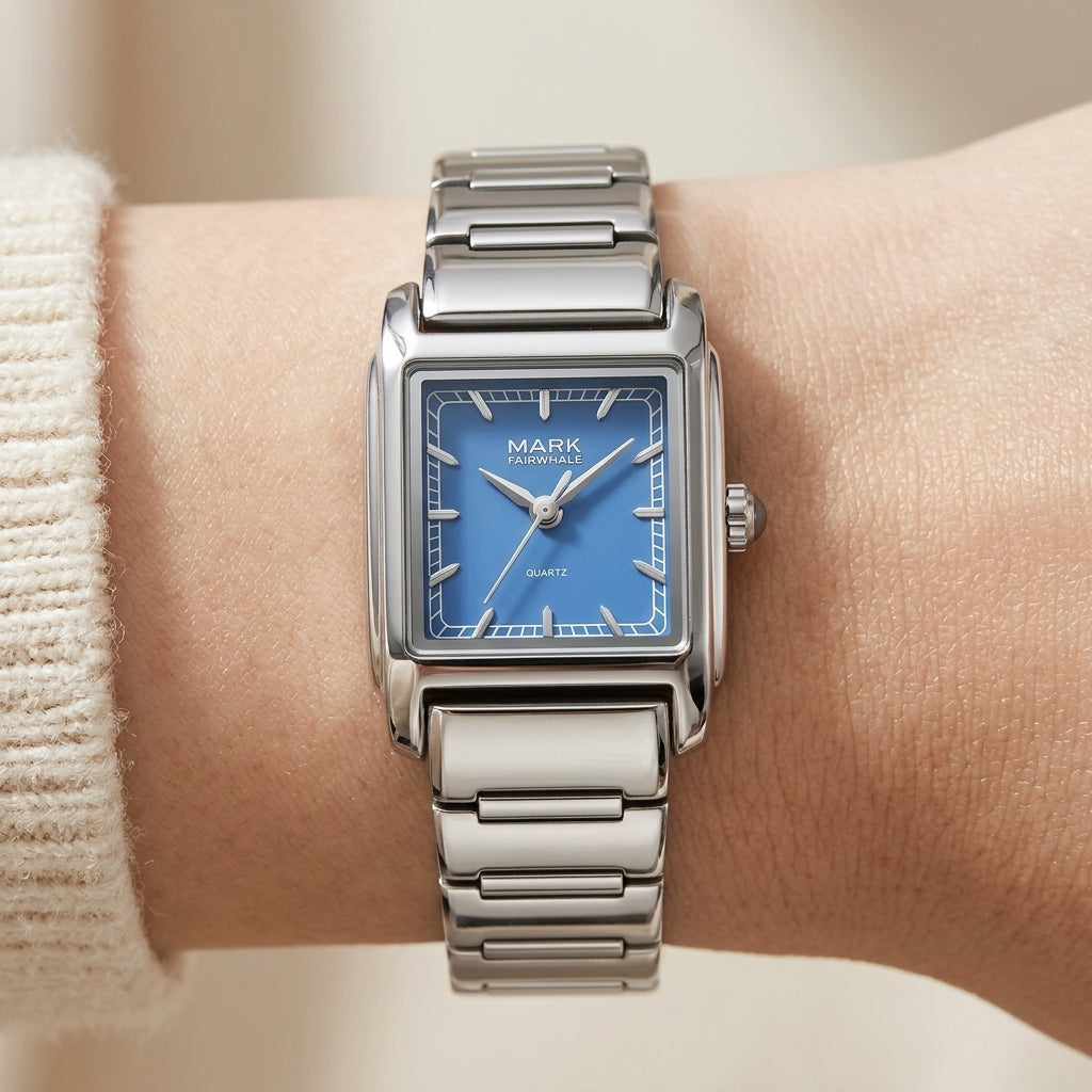 Silver watch with a blue face on a wrist against a neutral background