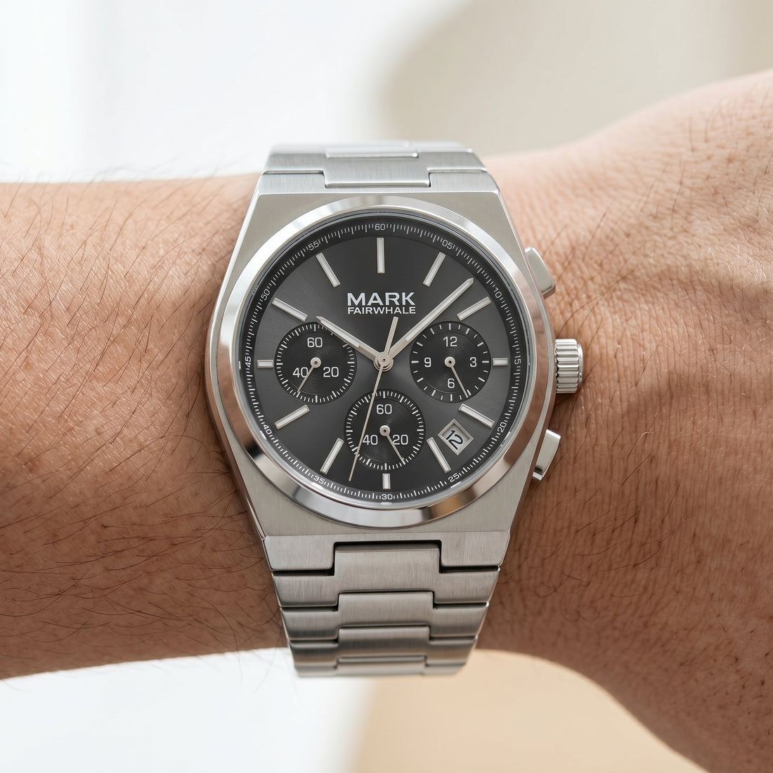 Silver watch with a dark face on a wrist, brand &