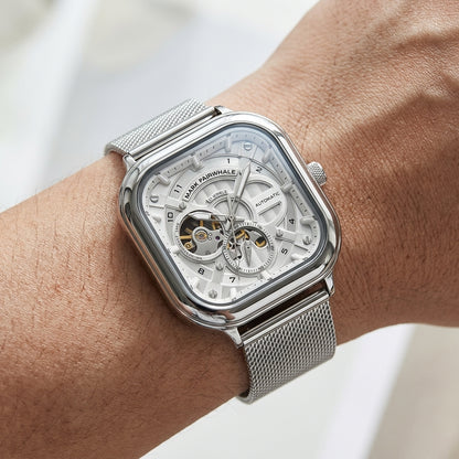 Silver watch with a detailed face on a wrist against a neutral background