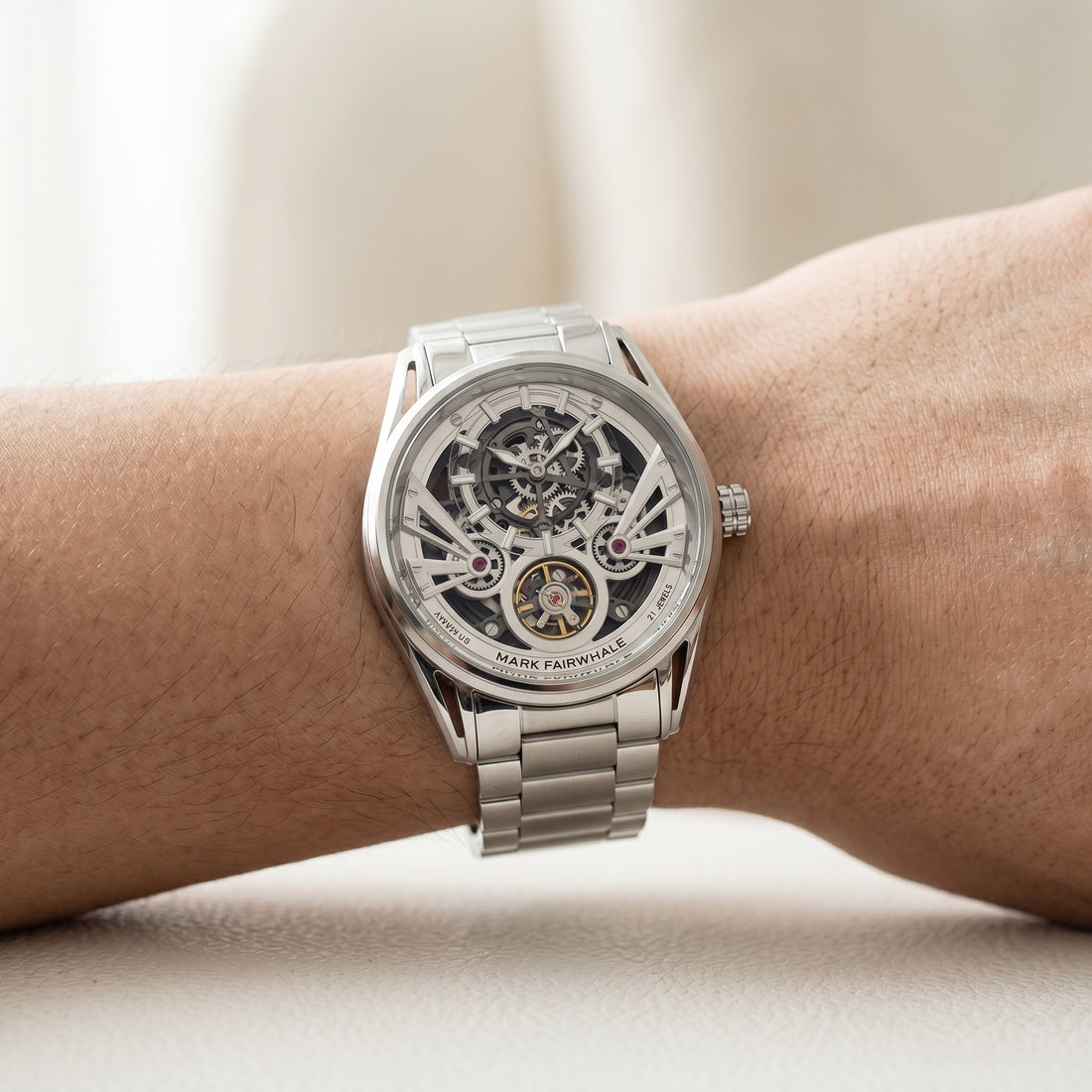 Silver watch with a detailed mechanism on a wrist against a neutral background