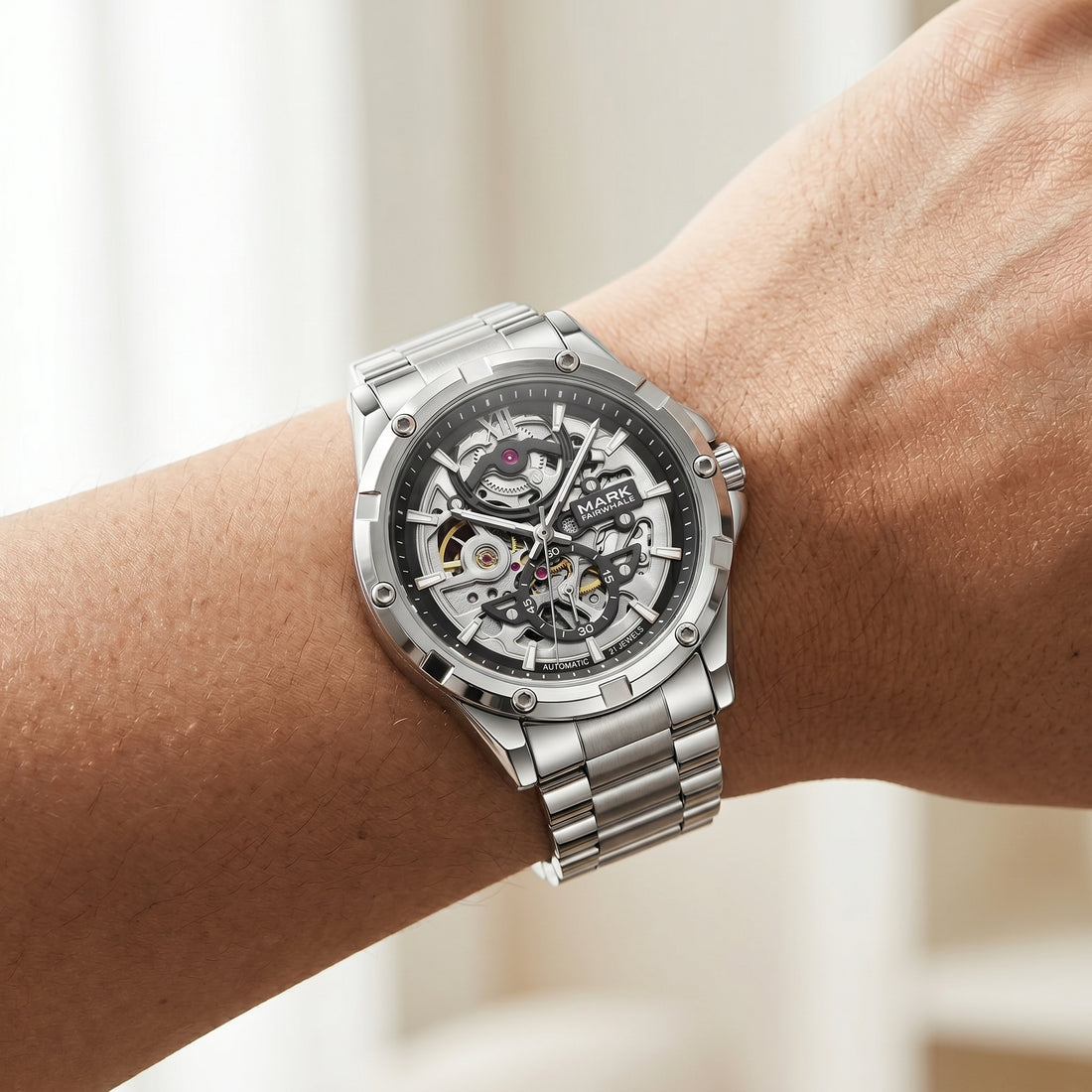 Silver watch with a visible mechanism on a wrist against a blurred background