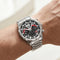 Silver watch with black face and red accents on a wrist against a neutral background