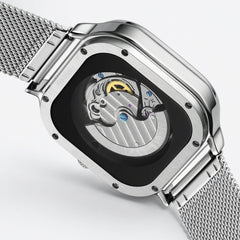 Silver watch with mesh band and open face design on a light gray background