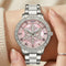 Silver watch with pink face and snowflake design on a wrist.